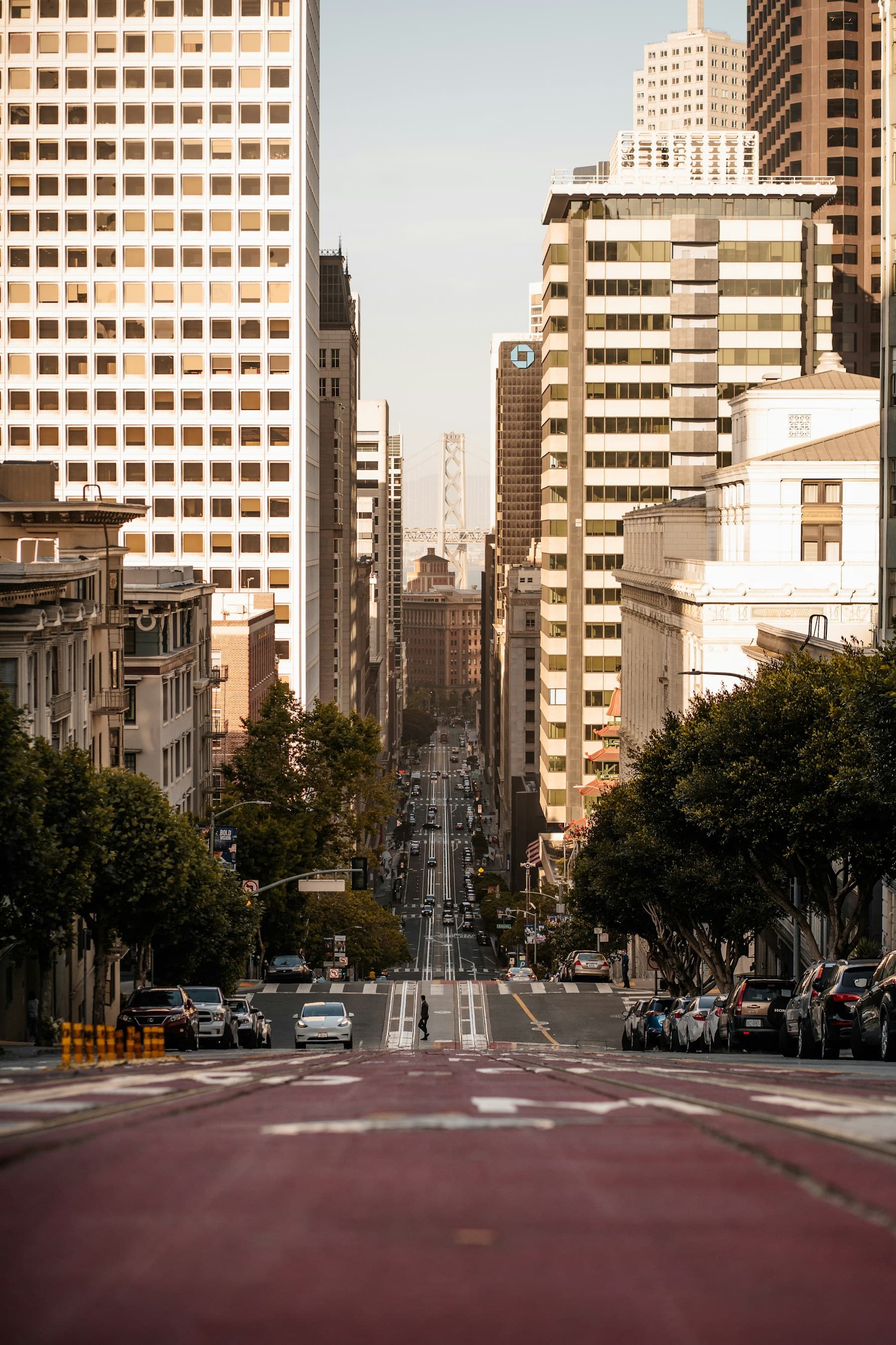 California Street dropping through downtown San Francisco, with the Bay Bridge framed between the buildings.